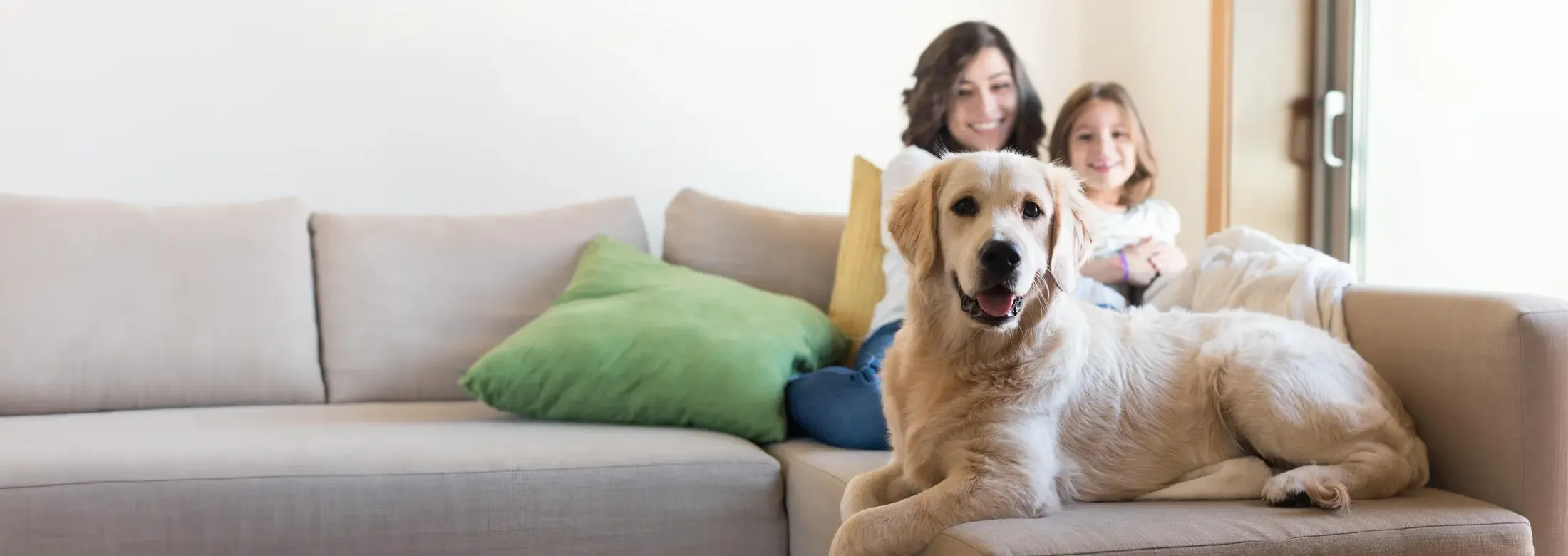 mom and daughter sitting on couch with dog